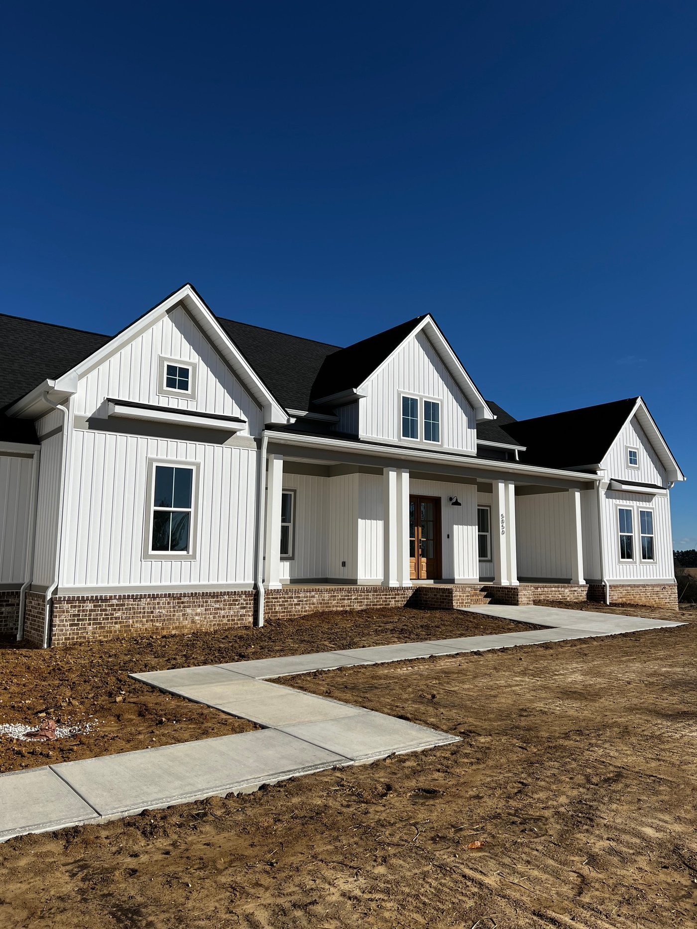 Downspout and gutter corner on a white farmhouse-style home by Gutter And Covers, Cookeville