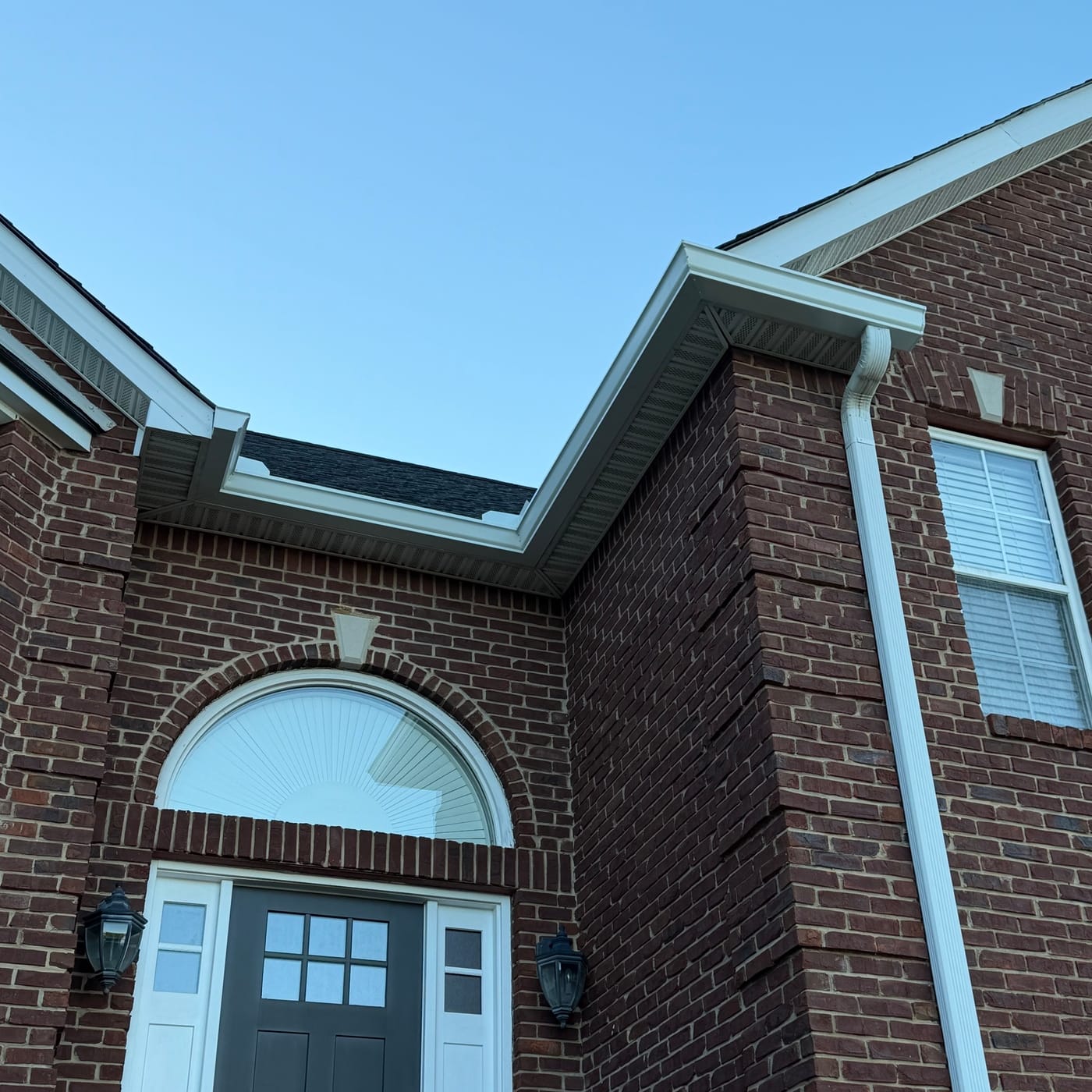White gutters and downspout over a brick entry by Gutter And Covers, Cookeville